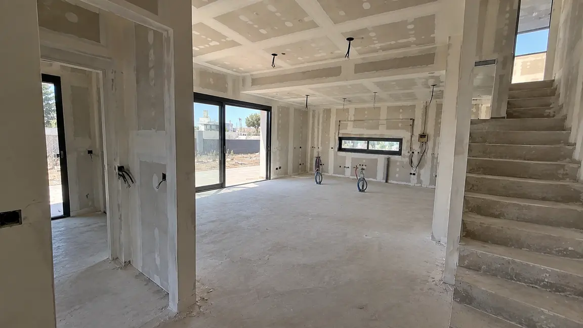 Interior de una vivienda de obra nueva de Reformas DLCP en fase de acabados, con tabiquería de pladur, techo registrable e instalaciones vistas antes del alicatado