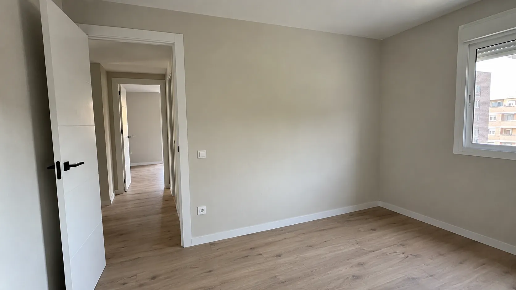 Habitación pintada por Reformas DLCP con la pared lisa, sin gotelé, rodapié blanco y suelo laminado